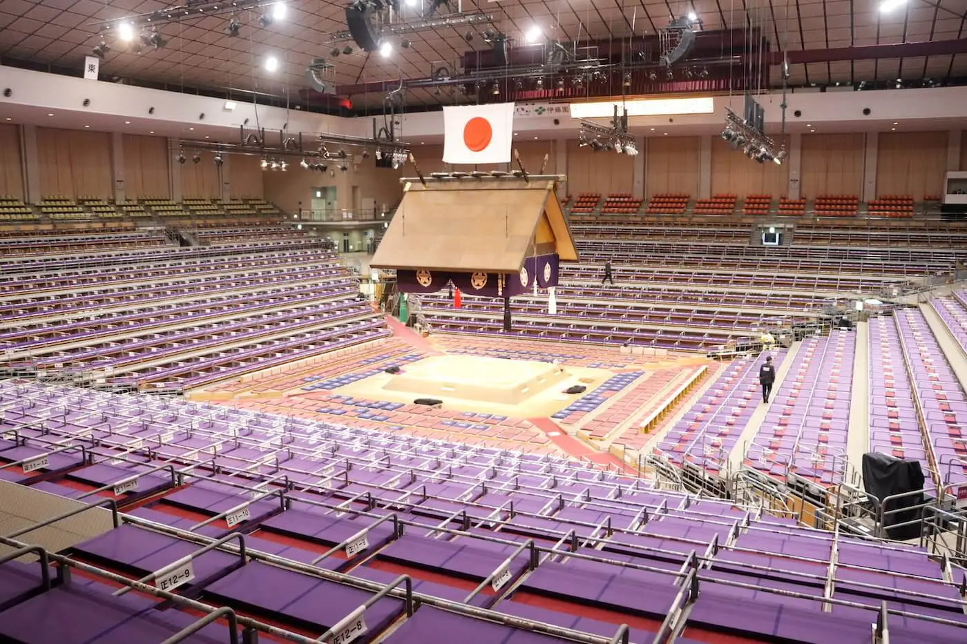 大相撲仕様に設営された福岡国際センターの内観。吊り屋根と土俵を囲む紫色の客席が並ぶ