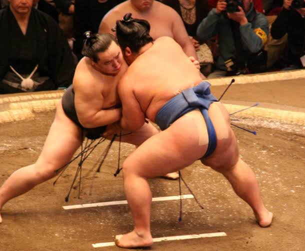 Two sumo wrestlers locked in a clinch on the dohyō during a bout